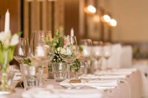 - une grande table avec des verres à vin et des fleurs dans l'établissement Gasthof Lauber, à Offenhausen