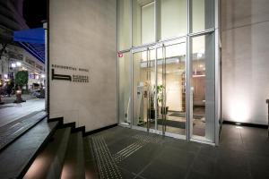 un bâtiment avec une porte en verre dans une rue de la ville dans l'établissement B:CONTE Asakusa, à Tokyo