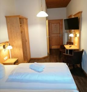 Schlafzimmer mit einem Bett, einem Schreibtisch und einem TV in der Unterkunft Gasthof Pension Altwirt in Sachsenkam
