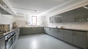 a large kitchen with gray cabinets and appliances at Greenhead Hostel in Greenhead