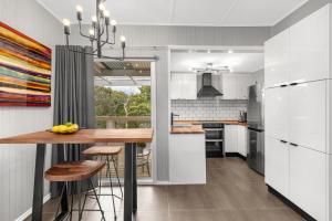a kitchen with white cabinets and a wooden table at Locarno Cottage in Hepburn Springs