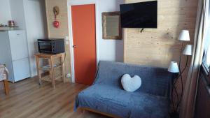 - un salon avec un canapé bleu et un oreiller pour le cœur dans l'établissement Appartement au pied du PIC du Midi à La MONGIE, à La Mongie
