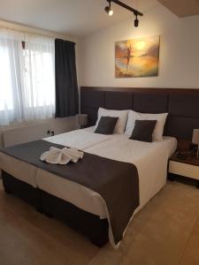 a bedroom with a large bed with a bow on it at Harry-apartments, Apart Hotel&spa Zoned Kopaonik - Special offer for Genius status for bookings during Early Booker Deal, additionally included parking, swimming pool and children under 13 stay free in Kopaonik +148 photos