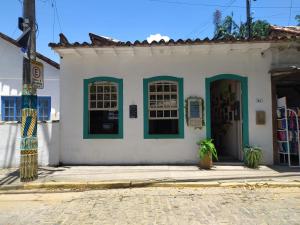 ein weißes Gebäude mit grünen Fenstern und einer Tür in der Unterkunft Com Verso e Prosa RePouso e Café in Paraty