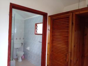 a bathroom with a toilet and a wooden door at Rosemary's Guesthouse in Praslin