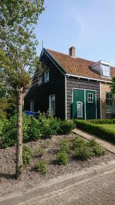 a black house with a green door and a tree at Klinket Zoutelande in Zoutelande