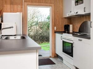 a kitchen with a sink and a door to a yard at 6 person holiday home in R m in Bolilmark