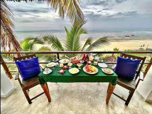 a table with food on a balcony with the beach at Villa Malaika in Jambiani