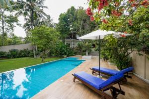 a swimming pool with two lounge chairs and an umbrella at The Villa Blue Sky in Unawatuna