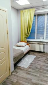 a bedroom with a bed with a yellow curtain at Гостиница На Набережной in Kotlas