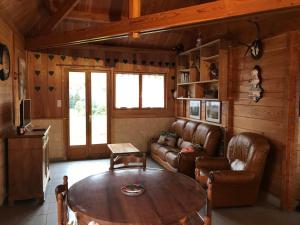 a living room with a table and leather furniture at Le chalet in Saint-Quentin-Lamotte-Croix-au-Bailly