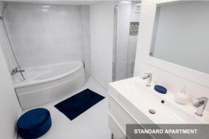 een witte badkamer met een witte wastafel en een blauwe kruk bij Savouir Bleu Suite near Danube in Boedapest