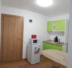 a kitchen with green cabinets and a white microwave on a refrigerator at Apartament 8 Budiu in Târgu-Mureş