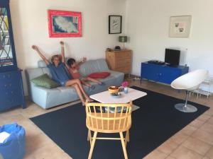 twee mensen zitten op een bank in een woonkamer bij Maison 100 m plage, 2 kms du port in L'Ile d'Yeu