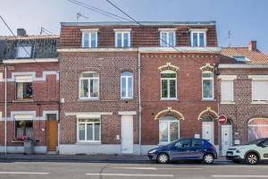 een bakstenen gebouw met auto's geparkeerd voor het bij studio Le relax in Roncq