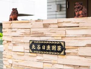 uma parede de pedra com um sinal em cima dela em 北谷日漁別荘 em Chatan