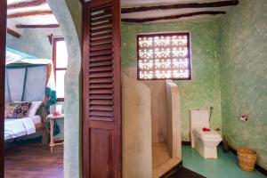 a bathroom with a shower and a toilet in a room at Mamamapambo Boutique Hotel in Jambiani