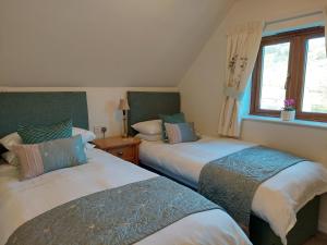 a bedroom with two beds and a window at Innisfree Cottage in Eyam