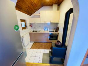 a small kitchen with white cabinets and a blue chair at Apartman Admir in Gladno Polje
