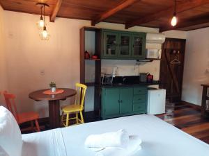 a kitchen with green cabinets and a table and a bed at Caminhos da Serra do Tabuleiro - Chalé do Lago in São Bonifácio +35 photos