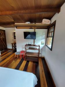 a living room with a tv and a desk with a computer at Caminhos da Serra do Tabuleiro - Chalé do Lago in São Bonifácio