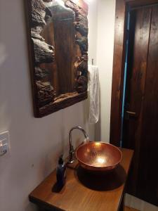 La salle de bains est pourvue d'un lavabo en cuivre sur un comptoir en bois. dans l'établissement Caminhos da Serra do Tabuleiro - Chalé do Lago, à São Bonifácio
