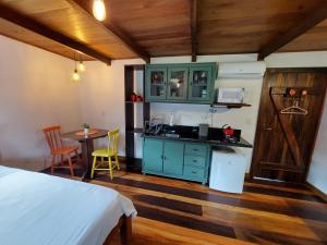 a bedroom with a bed and a kitchen with a table at Caminhos da Serra do Tabuleiro - Chalé do Lago in São Bonifácio