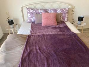 a bed with a purple blanket on top of it at Classic and Chic in Volos
