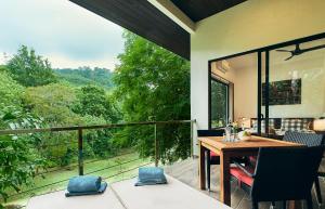 a screened in porch with a table and chairs on a balcony at Ranis Lodge in Kampung Padang Masirat