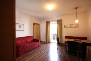 a living room with a red couch and a table at Residence Haus Ragen in Brunico