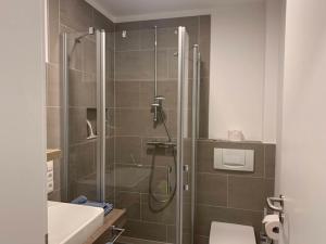 ein Bad mit einer Dusche, einem WC und einem Waschbecken in der Unterkunft Hotel Schmidt's Hoern in Horumersiel