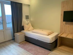 Dormitorio pequeño con cama y ventana en Hotel Schmidt's Hoern, en Horumersiel