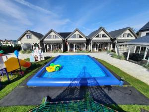 a swimming pool in front of a house at Holiday Homes 777 in Karwia