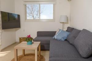 een woonkamer met een grijze bank en een tafel bij הגורן in Kefar Szold