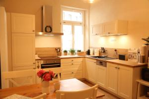 cocina con armarios blancos, mesa y ventana en Villa Adelinde, en Stromberg