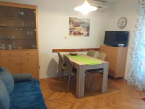 a living room with a table and chairs and a television at Apartments Picolo Paradiso Miljenko Debelić in Rab