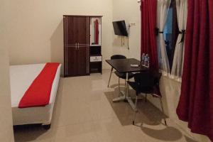 a bedroom with a bed and a desk and a table at RedDoorz Syariah near Sentani City Square in Weversdorp