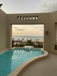 a swimming pool with a view of the ocean at The Villa at cove in Ras al Khaimah