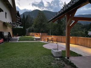 a backyard with a wooden deck and a table and benches at Apartments Maja by the river in Bohinj