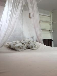 Una cama blanca con una almohada encima. en Green House Hostel, en Cabo Polonio