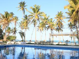 una piscina con palmeras y el océano en el fondo en Cristal Resort, en Paje