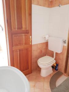 ein Badezimmer mit einem WC und einer Holztür in der Unterkunft VILLA AURA in Lipari