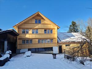 a large wooden house with snow in front of it at Grosses Ferienhaus für traumhafte Familienferien im Appenzellerland in Speicher