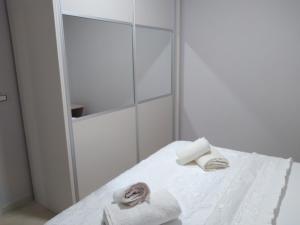 La salle de bains blanche est pourvue de serviettes et d'un miroir. dans l'établissement Eleana's Apartament, à Saranda