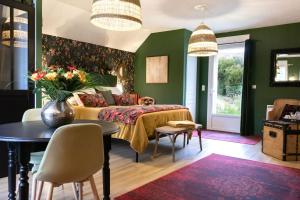 - une chambre avec des murs verts et un lit avec une table et des chaises dans l'établissement Les Patis, à Vouvray