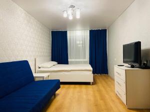 Habitación con cama, TV y sofá. en Апартаменты Бестхаус на Учебной 8, en Tomsk