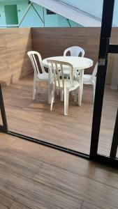 - Balcón con mesa blanca y sillas en Excelente apto em Caiobá a 3 quadras da praia!, en Matinhos