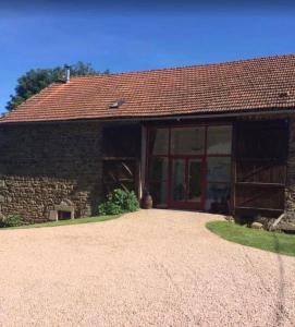 a stone barn with a large glass door at Combrailleurs Gite in Espinasse
