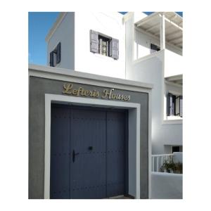 a white building with a blue garage door at Lefteris Houses in Karterados