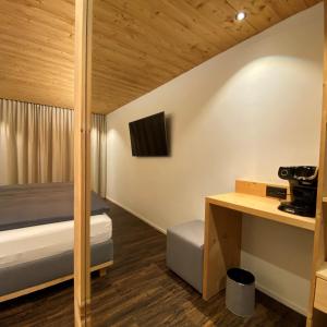 ブリゲルにあるAdults Only Hotel Mulin - Das Erwachsenen-Hotel in den Bergenのベッドとデスクが備わる小さな客室です。